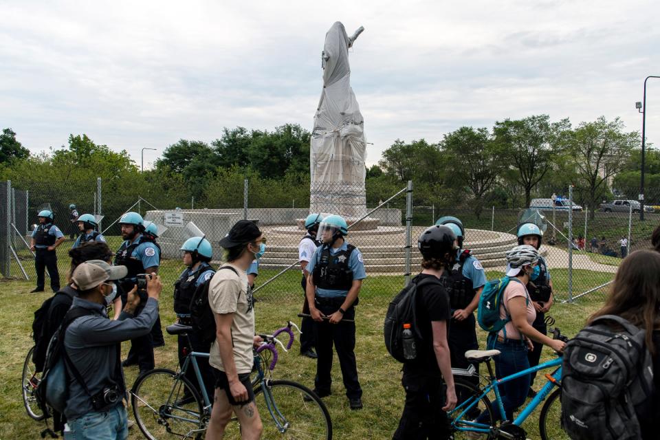 Activists protest around a statue of Christopher Columbus near Roosevelt Rd. and Columbus Dr. while police stand by,, Monday, July 20, 2020 in Chicago.