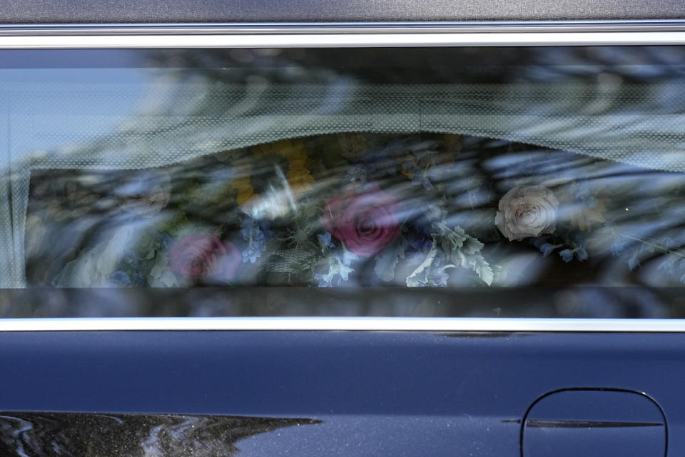 The casket of former first lady Rosalynn Carter is covered in flowers in the hearse as family members participate in a wreath laying ceremony at the Rosalynn Carter Health & Human Services complex on the campus of Georgia Southwestern State University, Monday, Nov. 27, 2023, in Americus, Ga. The former first lady died on Nov. 19. She was 96. (AP Photo/John Bazemore, Pool)