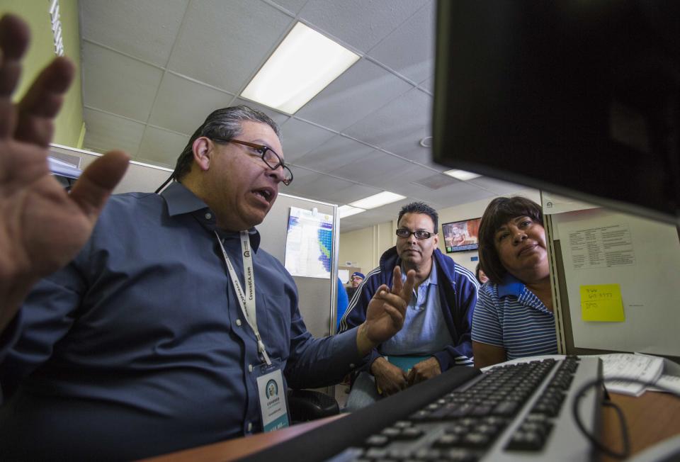 Staff Thomas Sundoval, left, assists Jaime Sanchez, center, 50, and his wife Carmen Castro, right,, 50, during a health care enrollment event at AltaMed Health Insurance Resource Center, Monday, March 31, 2014, in Los Angeles. Monday marks this year's open enrollment deadline, but consumers will get extra time to finish their applications. (AP Photo/Ringo H.W. Chiu)