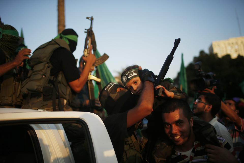 Hamas militants celebrate with people in what they said was a victory over Israel, in Gaza City