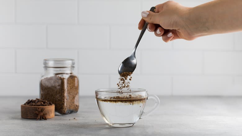 instant coffee powder spooned into water