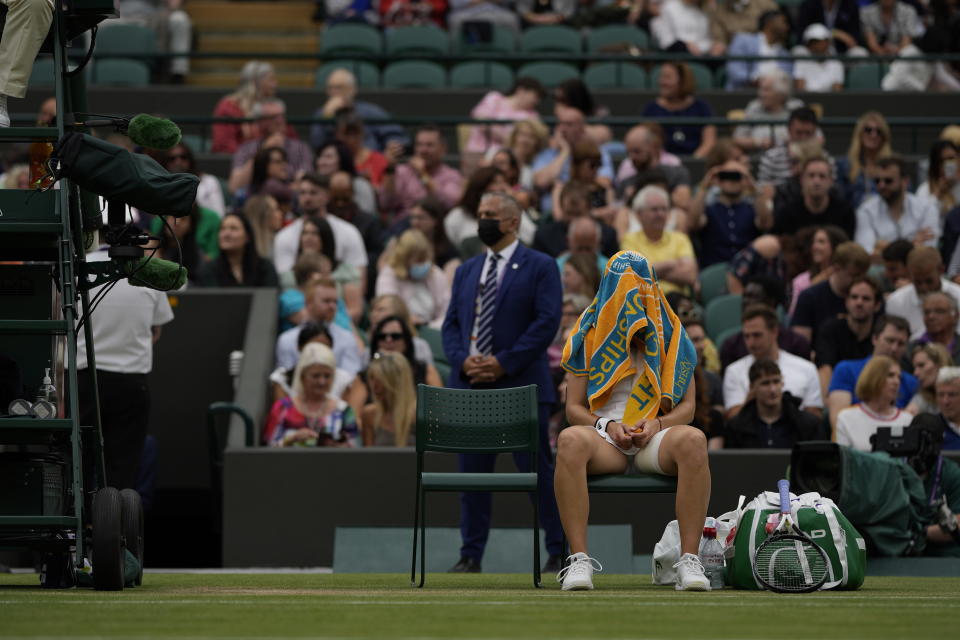Czech Republic's Karolina Muchova sits with a towel over her face during the women's singles quarterfinals match against Germany's Angelique Kerber on day eight of the Wimbledon Tennis Championships in London, Tuesday, July 6, 2021.(AP Photo/Alastair Grant)