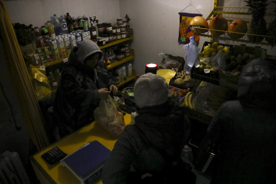 A vendor uses a flashlight inside a small food shop during a power outage in Chisinau, Moldova, Wednesday, Nov. 23, 2022. Moldova suffered massive power outages on Wednesday after Russian strikes on neighboring Ukraine's energy infrastructure left the small non-European Union country in the dark for the second time in little more than a week. (AP Photo/Aurel Obreja)