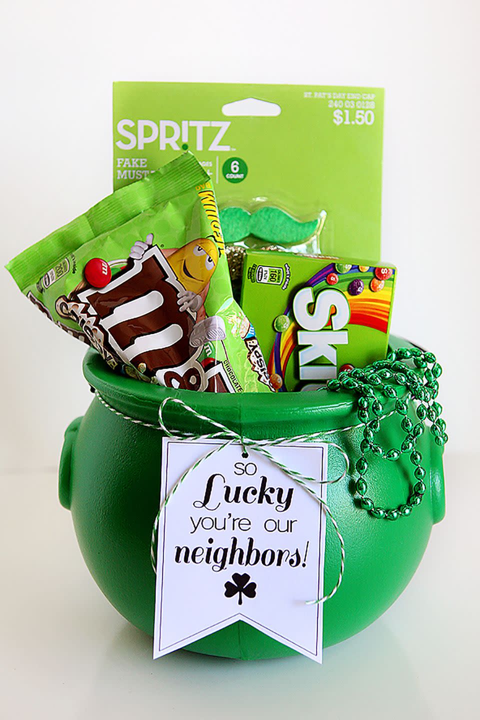 green caldron filled with st patrick's day candy and other goodies with printable gift tag that says so luck you're our neighbors