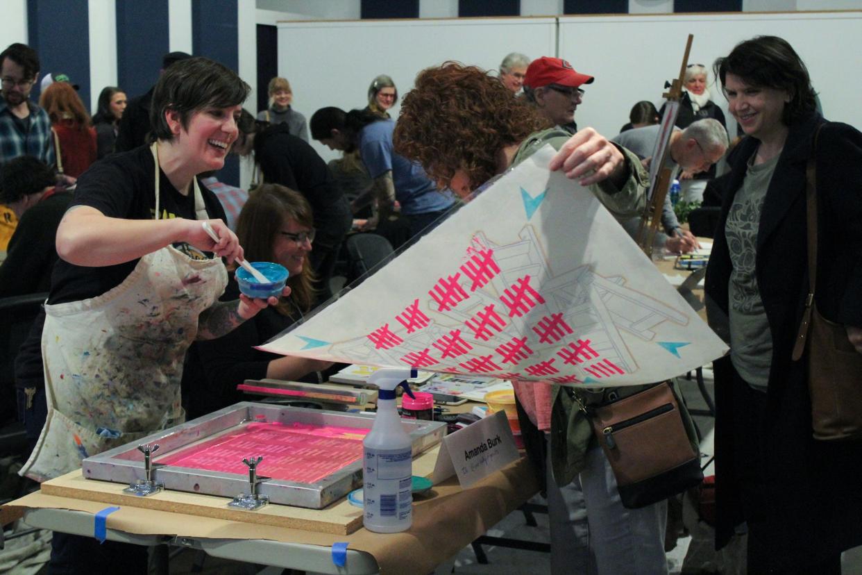 (L) Athens printmaker Amanda Burk interacts with a patron at the 2019 Monster Drawing Rally at Cine in Athens, Ga. Burk is among the artists that will be participating in the Really Big Art Rally on Mar. 25, 2023.