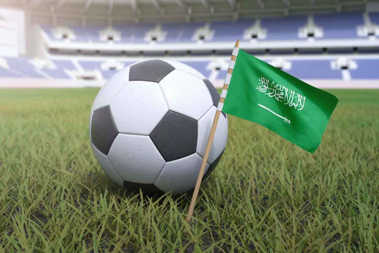Saudi Arabian flag in stadium field with soccer football