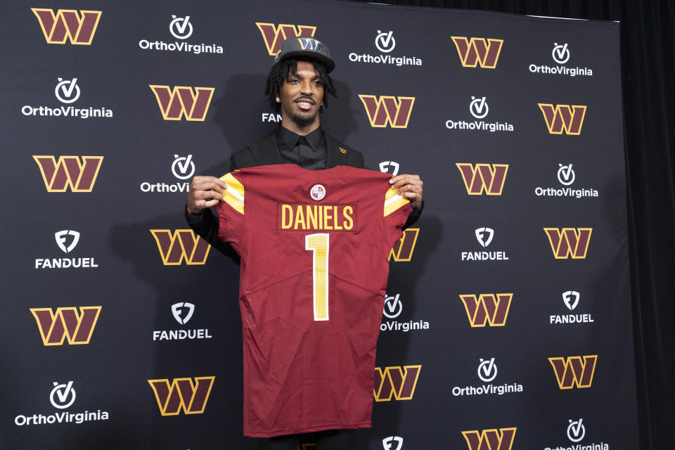 Washington Commanders' first round draft pick Jayden Daniels holds his Commanders jersey during an NFL football news conference in Ashburn, Va., Friday, April 26, 2024. (AP Photo/Manuel Balce Ceneta)