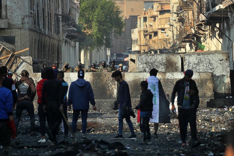 Anti-government protesters gather near barriers set up by security forces to close Rasheed Street during ongoing protests in Baghdad, Iraq, Thursday, Dec. 5, 2019. (AP Photo/Khalid Mohammed)