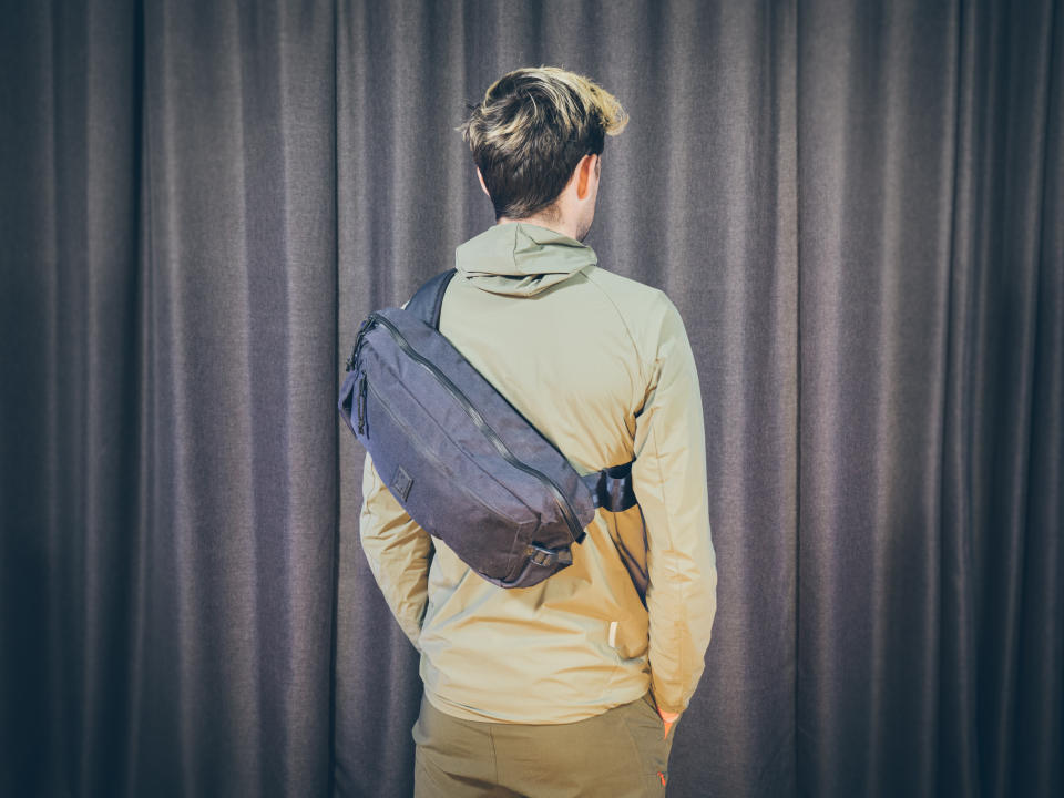 Will Jones, wearing the Chrome Kadet, one of the best backpacks for cycling, stands in front of a wall