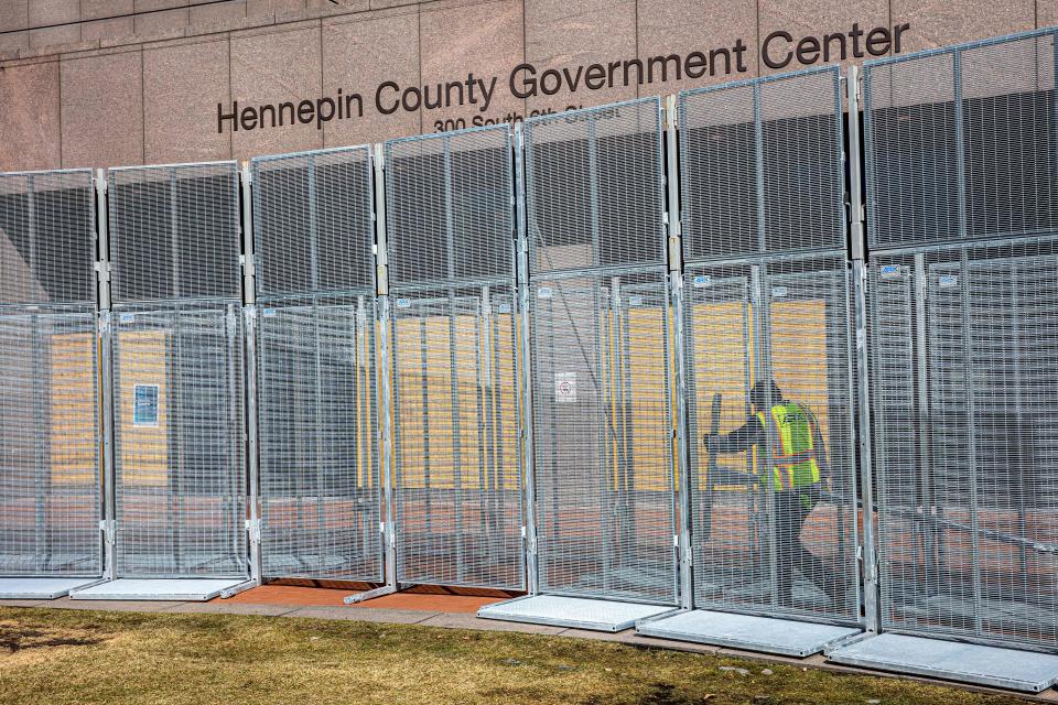 A worker installs security fencing at the Hennepin County government headquarters in Minneapolis on March 3. Security measures are being increased downtown in preparation for the trial of former police officer Derek Chauvin.