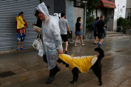 A woman and her dog dress in raincoats as they walk while Typhoon Haima approaches in Hong Kong, China, October 21, 2016 . REUTERS/Bobby Yip