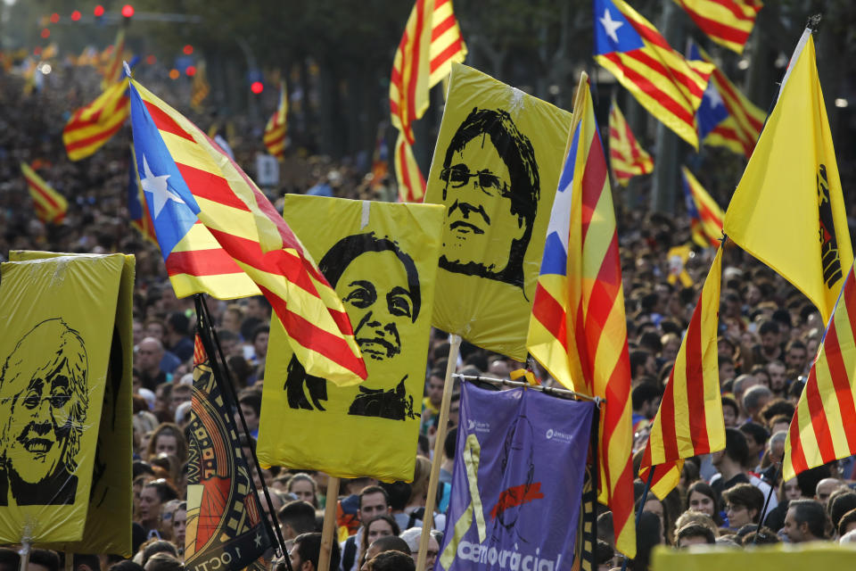 Protestors hold pictures of Catalan high-profile separatist politicians, Clara Ponsati, Anna Gabriel and Carles Puidgemont, from left to right, who are fugitives from Spanish law after fleeing the country, during a demonstration in Barcelona, Spain, Friday, Oct. 18, 2019.The Catalan regional capital is bracing for a fifth day of protests over the conviction of a dozen Catalan independence leaders. Five marches of tens of thousands from inland towns are converging in Barcelona's center for a mass protest. (AP Photo/Emilio Morenatti)