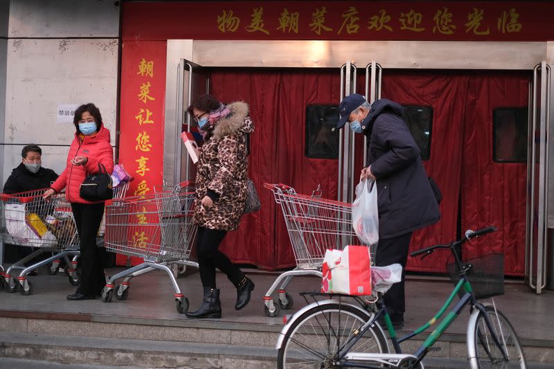 People wearing face masks walk out of a supermarket, as the country is hit by an outbreak of the new coronavirus, in Beijing