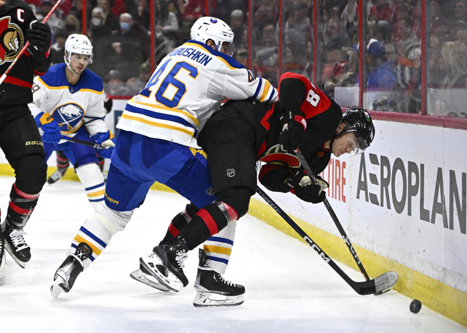 Buffalo Sabres defenseman Ilya Lyubushkin (46) checks Ottawa Senators left wing Tim Stutzle (18) into the boards during the second period of an NHL hockey game in Ottawa, Ontario, Sunday, Jan. 1, 2023. (Justin Tang/The Canadian Press via AP)