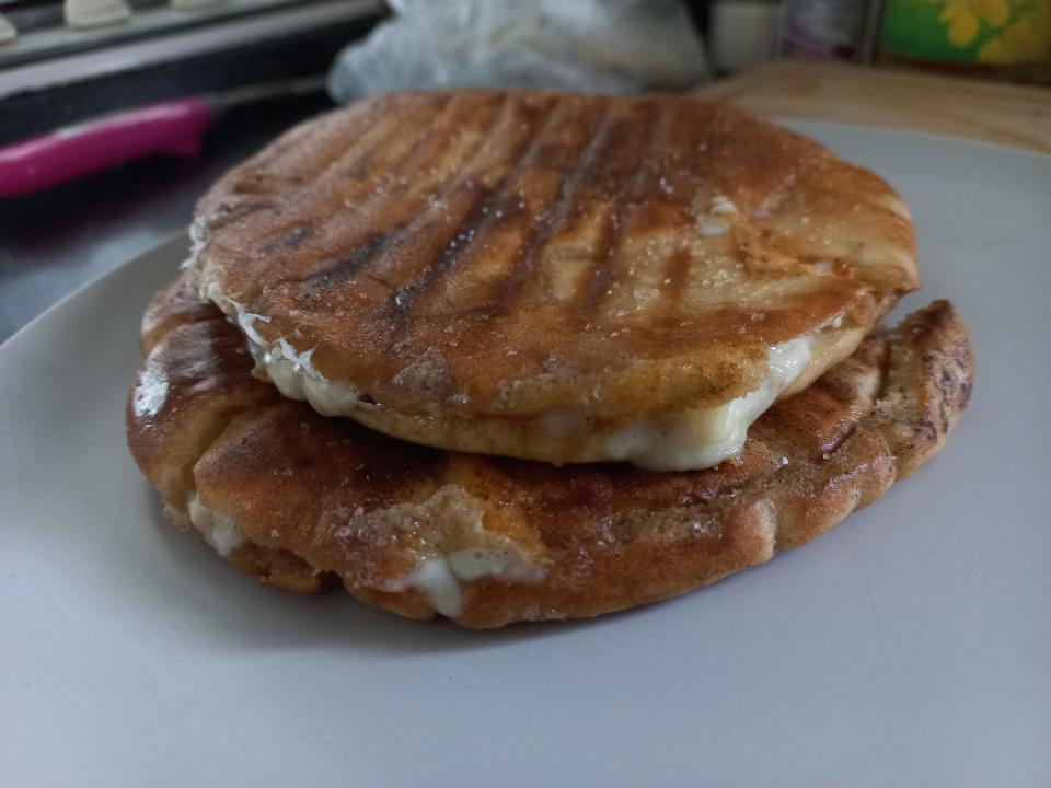 Grilled sandwich with melted cheese on a white plate