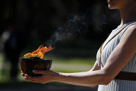 An actress, playing the role of the priestess, holds the flame during the flame lighting ceremony at the closed Ancient Olympia site, birthplace of the ancient Olympics in southern Greece, Thursday, March 12, 2020. Greek Olympic officials are holding a pared-down flame-lighting ceremony for the Tokyo Games due to concerns over the spread of the coronavirus. Both Wednesday's dress rehearsal and Thursday's lighting ceremony are closed to the public, while organizers have slashed the number of officials from the International Olympic Committee and the Tokyo Organizing Committee, as well as journalists at the flame-lighting. (AP Photo/Thanassis Stavrakis)