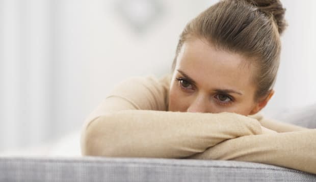 stressed young woman sitting on sofa