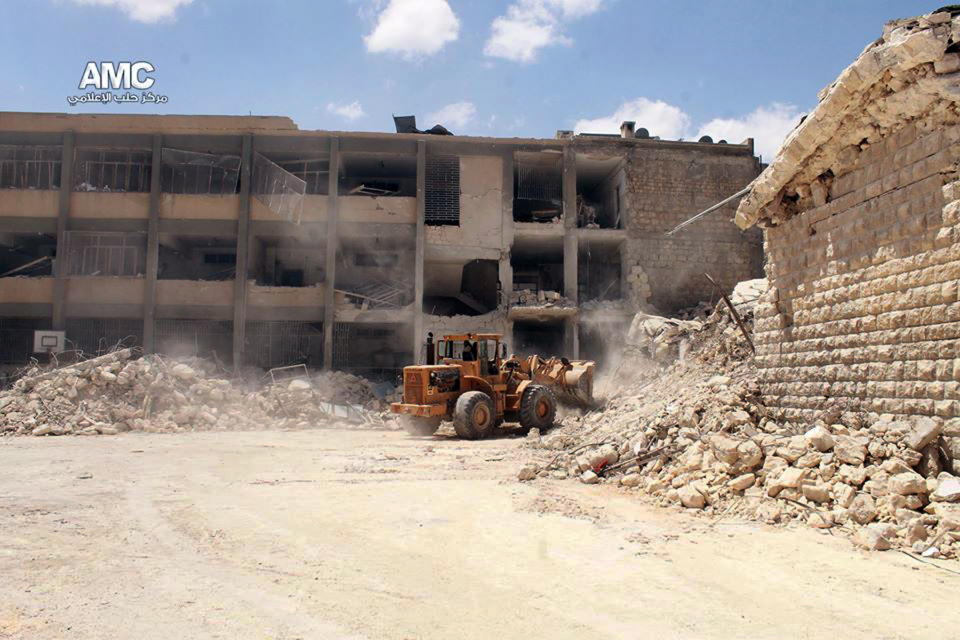 This photo provided by the anti-government activist group Aleppo Media Center (AMC), which has been authenticated based on its contents and other AP reporting, shows a bulldozer removing the wreckage of a destroyed school that was hit by a Syrian government air strike in Aleppo, Syria, Wednesday, April 30, 2014. Many people were killed and wounded, including several children, activists reported. (AP Photo/Aleppo Media Center AMC)