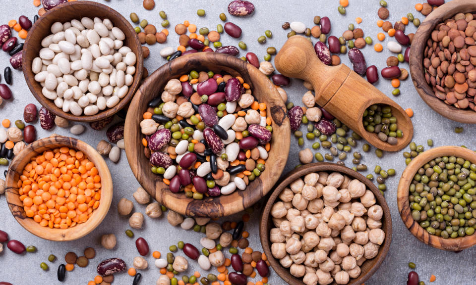 A white table with wood bowls filled with different types of legumes, which are a potassium-rich food