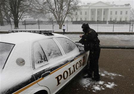 A member of the U.S. Secret Service Uniformed Division brushes snow off his vehicle in front of the White House in Washington during a snowstorm January 21, 2014. REUTERS/Larry Downing