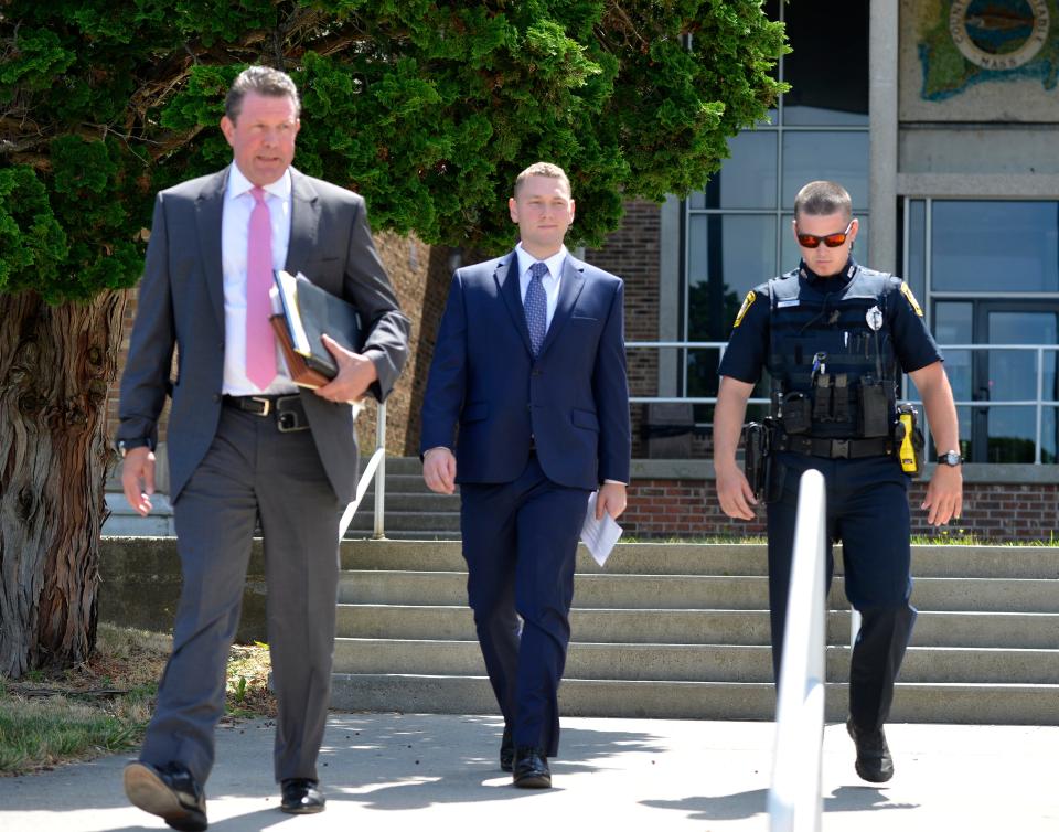A Barnstable police officer, right, escorts Reid Mason, center, and his attorney Peter Lloyd out of Barnstable District Court after Mason's arraignment Wednesday on improper gun storage charges. Reid is the son of Massachusetts state police Superintendent Christopher Mason.