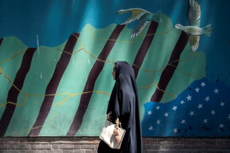 A woman walks in front of an anti-U.S. mural in Tehran