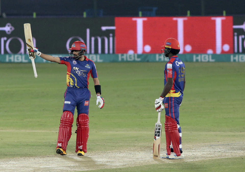 Karachi Kings Babar Azam, left, raises his bat to celebrate his fifty against Lahore Qalandars during the final of their Pakistan Super League T20 cricket match at National Stadium in Karachi, Pakistan, Tuesday, Nov. 17, 2020. (AP Photo/Fareed Khan)