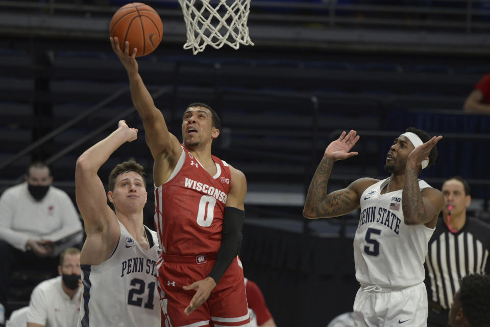 Wisconsin's D'Mitrik Trice (0) drives to the basket between Penn State's John Harrar (21) and Jamari Wheeler (5) during the second half of an NCAA college basketball game, Saturday, Jan. 30, 2021, in State College, Pa. (AP Photo/Gary M. Baranec)