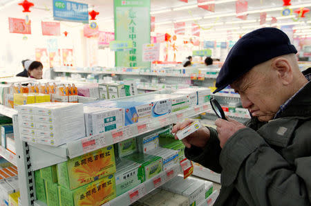 An elderly man uses a magnifiying glass to see the description on a pack of medicine at a pharmacy in Dandong, Liaoning province, China, March 30, 2011. REUTERS/Jacky Chen/File Photo