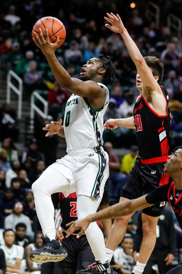 Detroit Cass Tech guard Corey Sadler Jr. makes a layup against Grand Blanc guard RJ Taylor during the second half of Cass Tech's 62-56 overtime win in the Division 1 semifinal at Breslin Center on Friday, March 24, 2023.