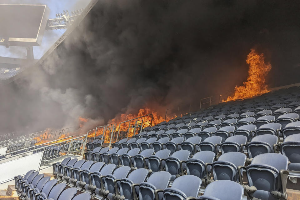 In this photo provided by the Denver Fire Department, a fire burns at Empower Field at Mile High stadium in Denver, Thursday, March 24, 2022. Firefighters have extinguished a blaze that torched several rows of seats and a suite area at the Denver Broncos' stadium. The fire broke out in the third-level and burned at least six rows of seats in two sections. (Denver Fire Department via AP)