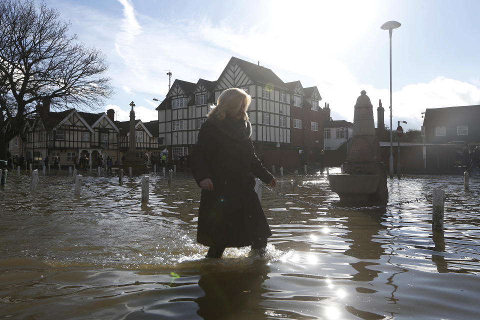 A woman wades through a flooded street, in Datchet, England, Monday, Feb. 10, 2014. The River Thames has burst its banks after reaching its highest level in years, flooding riverside towns upstream of London. Residents and British troops had piled up sandbags in a bid to protect properties from the latest bout of flooding to hit Britain. But the floods overwhelmed their defences Monday, leaving areas including the centre of the village of Datchet underwater. (AP Photo/Sang Tan)