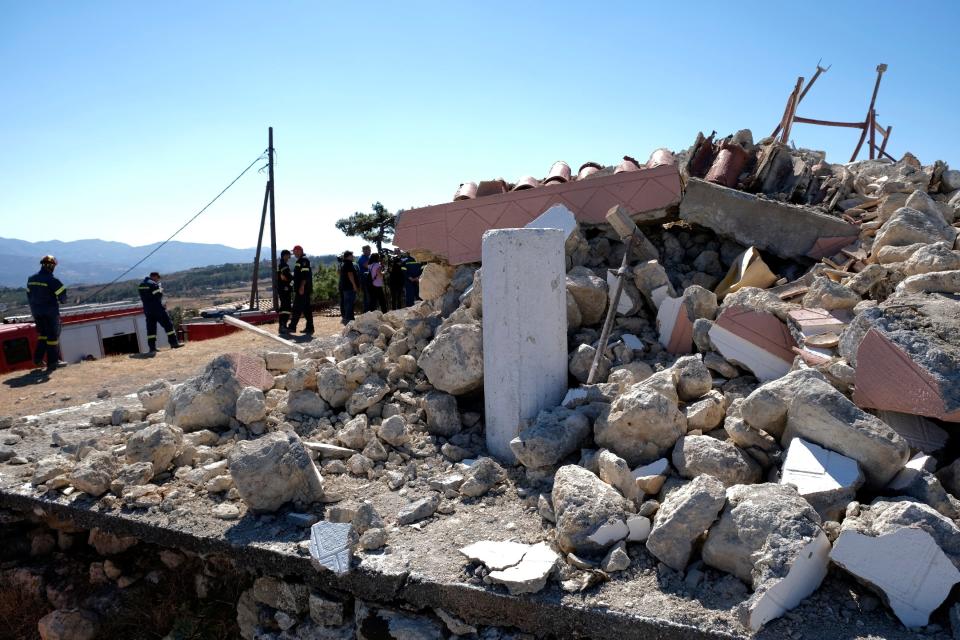 Firefighters stand next to a demolished Greek Orthodox church of Profitis Ilias (AP)