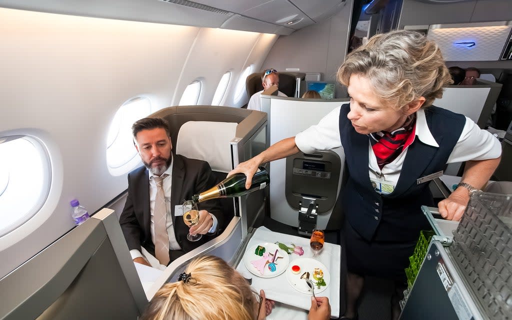 A member of cabin crew pours a glass of champagne in business class (Getty Images)