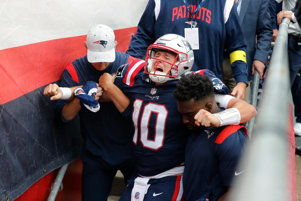 New England Patriots quarterback Mac Jones (10) is helped off the field after suffering a leg injury with less than two minutes to play in the second half of an NFL football game against the Baltimore Ravens, Sunday, Sept. 25, 2022, in Foxborough, Mass. (AP Photo/Michael Dwyer)