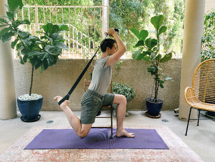 Man sitting on a chair taking a variation of Dancer Pose in yoga
