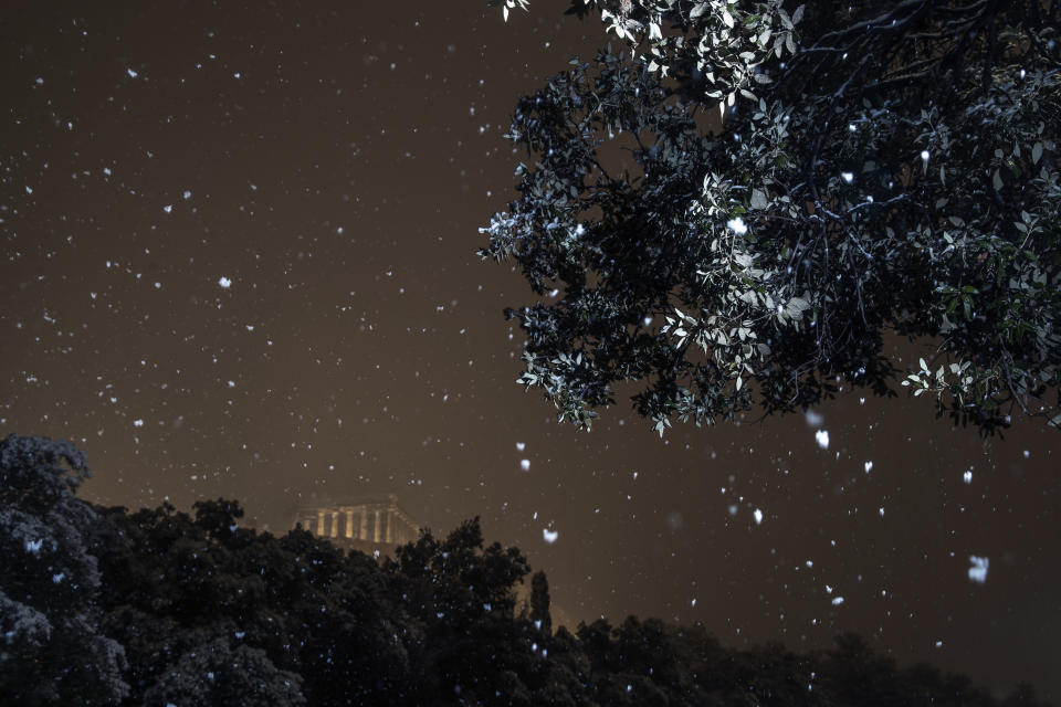 The ancient Parthenon temple on the Acropolis hill is illuminated during a snowfall in central Athens , early Tuesday, Feb. 16, 2021. A cold weather front has hit Greece, sending temperatures plunging from the low 20s degrees Celsius (around 70 Fahrenheit) on Friday to well below freezing on Monday, and seeing snowfall in central Athens. (AP Photo/Petros Giannakouris)