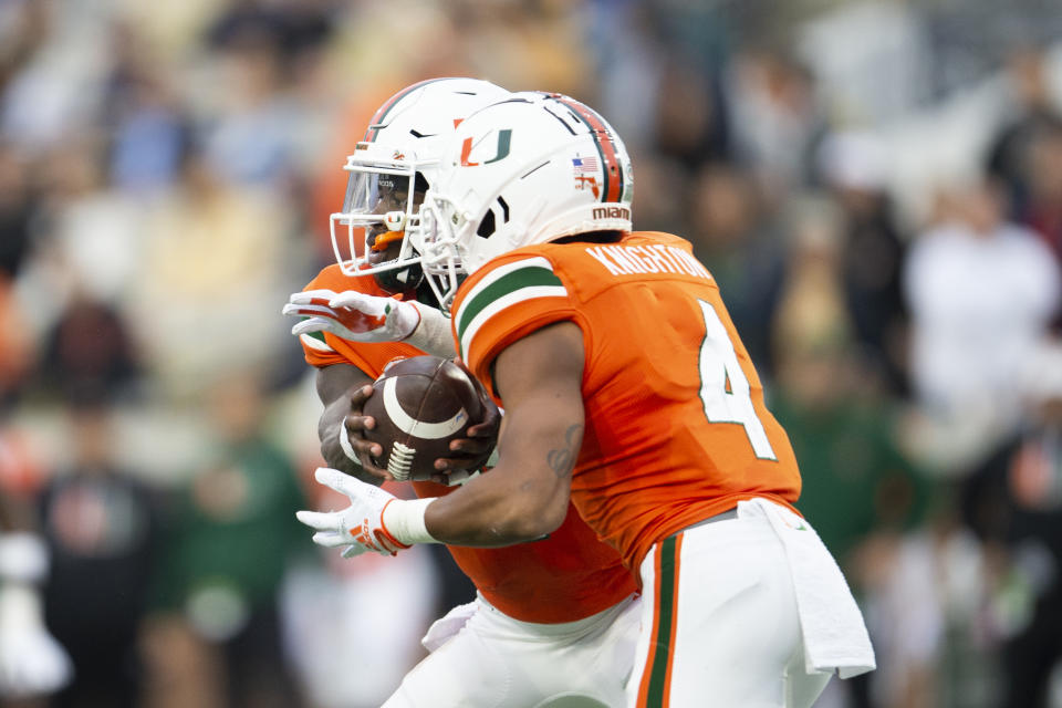 Miami quarterback Jacurri Brown, left, hands off to running back Jaylan Knighton in the first half of an NCAA college football game against Georgia Tech, Saturday, Nov. 12, 2022, in Atlanta. (AP Photo/Hakim Wright Sr.)