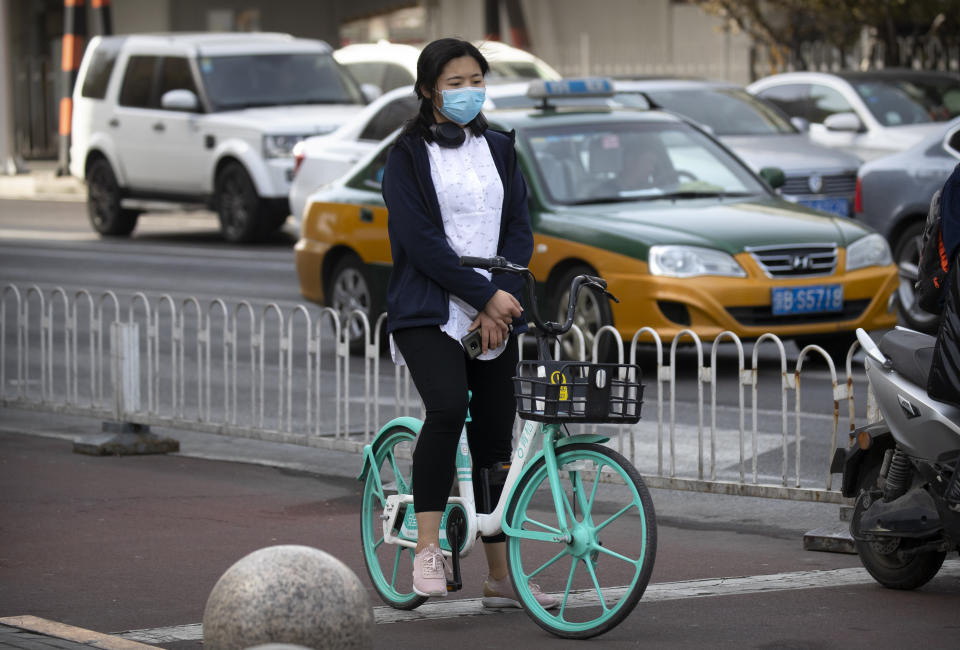 A cyclist pauses during a national moment of mourning for victims of the coronavirus, in Beijing on Saturday, April 4, 2020. With air raid sirens wailing and flags at half-staff, China on Saturday held a three-minute nationwide moment of reflection to honor those who have died in the coronavirus outbreak, especially "martyrs" who fell while fighting what has become a global pandemic. (AP Photo/Mark Schiefelbein)