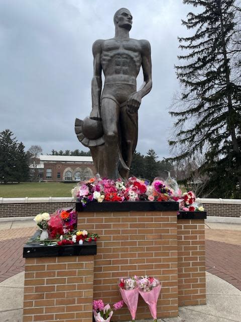 Flowers laid at the Spartan statue at Michigan State University mark one year since a deadly campus shooting. (Feb. 13, 2024)