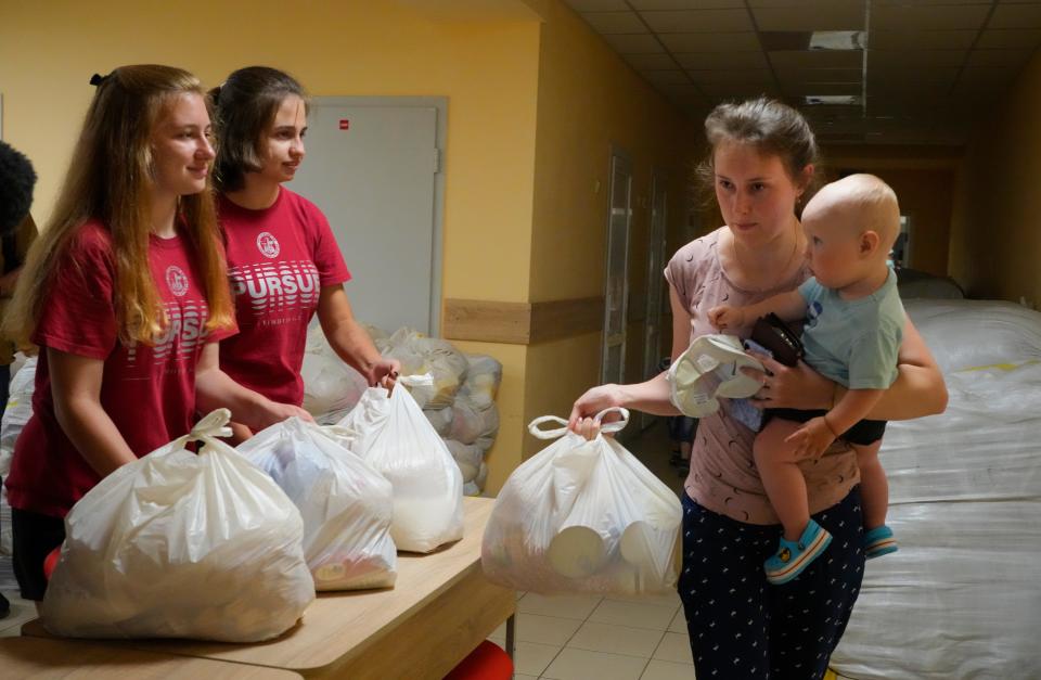 A woman carries her child as she receives humanitarian aid provided by local authorities in Selidovo, Donetsk region, Ukraine, Tuesday, June 14, 2022.