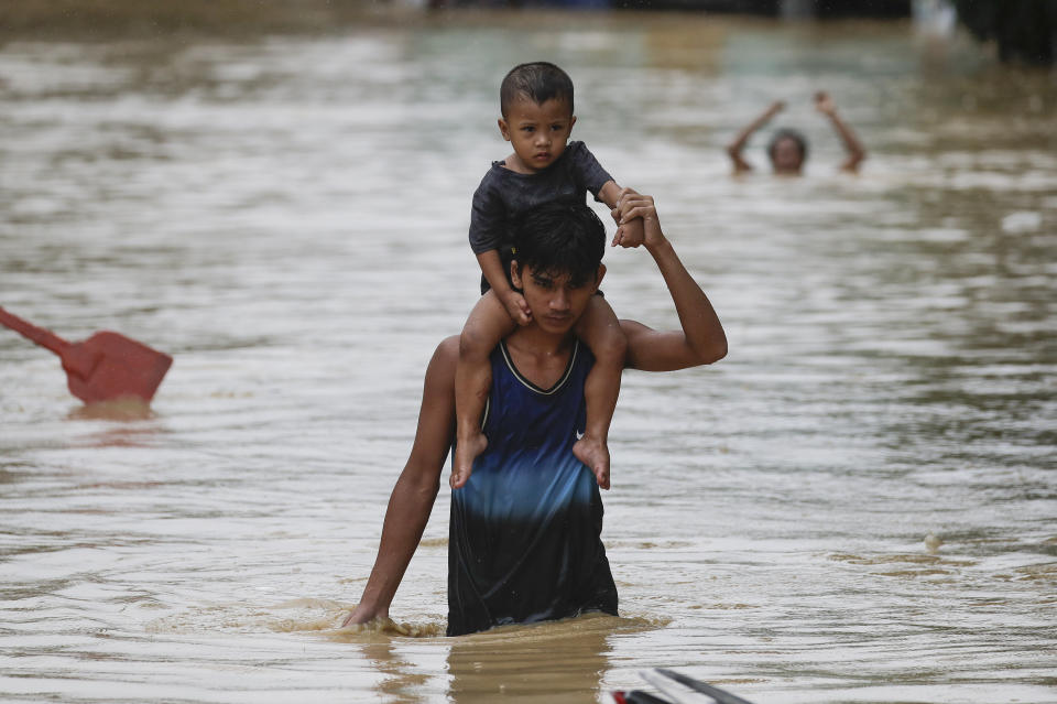 A man carries a boy on his shoulders as they negotiate floodwaters due to Typhoon Vamco in Marikina, Philippines on Thursday, Nov. 12, 2020. A typhoon swelled rivers and flooded low-lying areas as it passed over the storm-battered northeast Philippines, where rescuers were deployed early Thursday to help people flee the rising waters.(AP Photo/Aaron Favila)