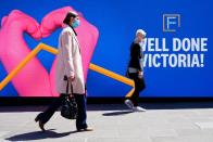 People walk past a 'Well Done Victoria' sign after coronavirus disease restrictions were eased in Melbourne