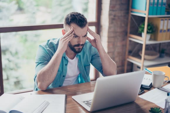 A young man stresses as he looks at his laptop