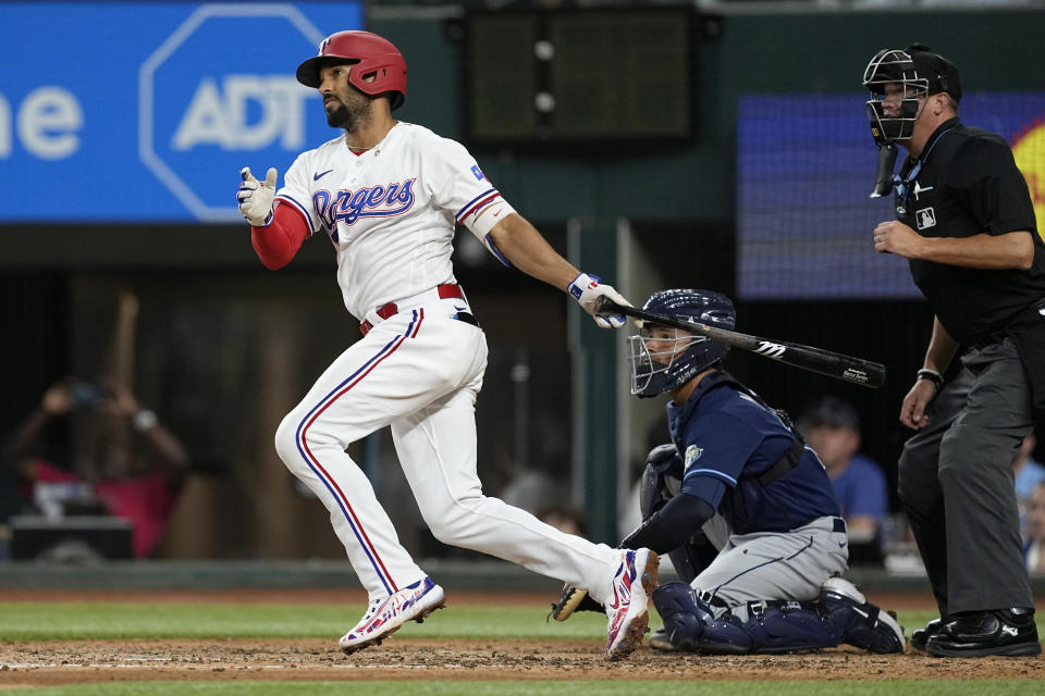 Texas Rangers' Marcus Semien follows through on a single next to Tampa Bay Rays catcher Francisco Mejia and umpire Cory Blaser during the fifth inning of a baseball game Tuesday, July 18, 2023, in Arlington, Texas. (AP Photo/Tony Gutierrez)