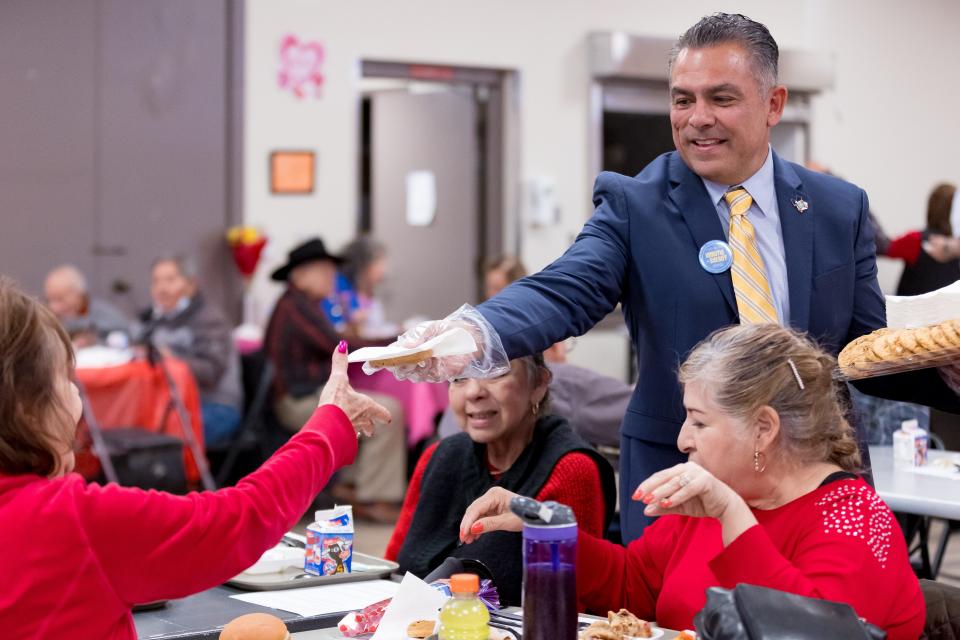 El Paso County sheriff candidate Ryan Urrutia passes out cookies as he campaigns on Valentine's Day at the Eastside Senior Citizen Center in El Paso.