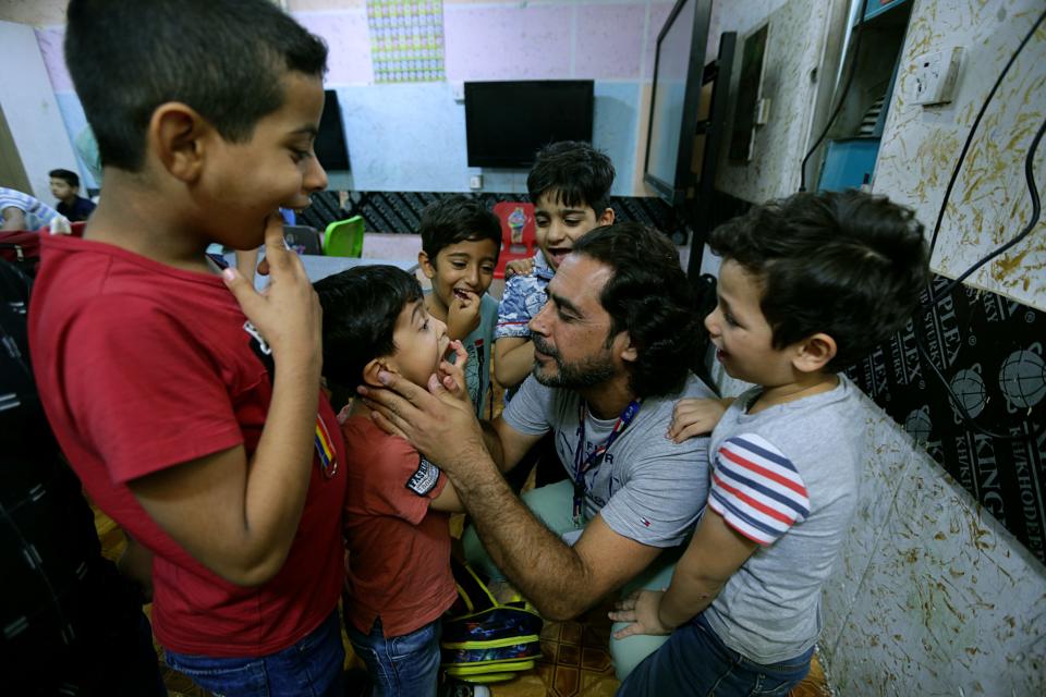 In this Wednesday, Oct. 17, 2018, Hisham al-Dahabi, center, a social worker and philanthropist examines the teeth of students at the orphanage he runs in the heart of Baghdad, Iraq. Prime Minister-designate Adel Abdul-Mahdi opened an online portal for anyone to apply to run Iraq’s 22 ministries and take over the posts that have come to be associated with patronage and graft. Al-Dahabi said he applied reluctantly to be the minister of labor and social affairs. (AP Photo/Hadi Mizban)