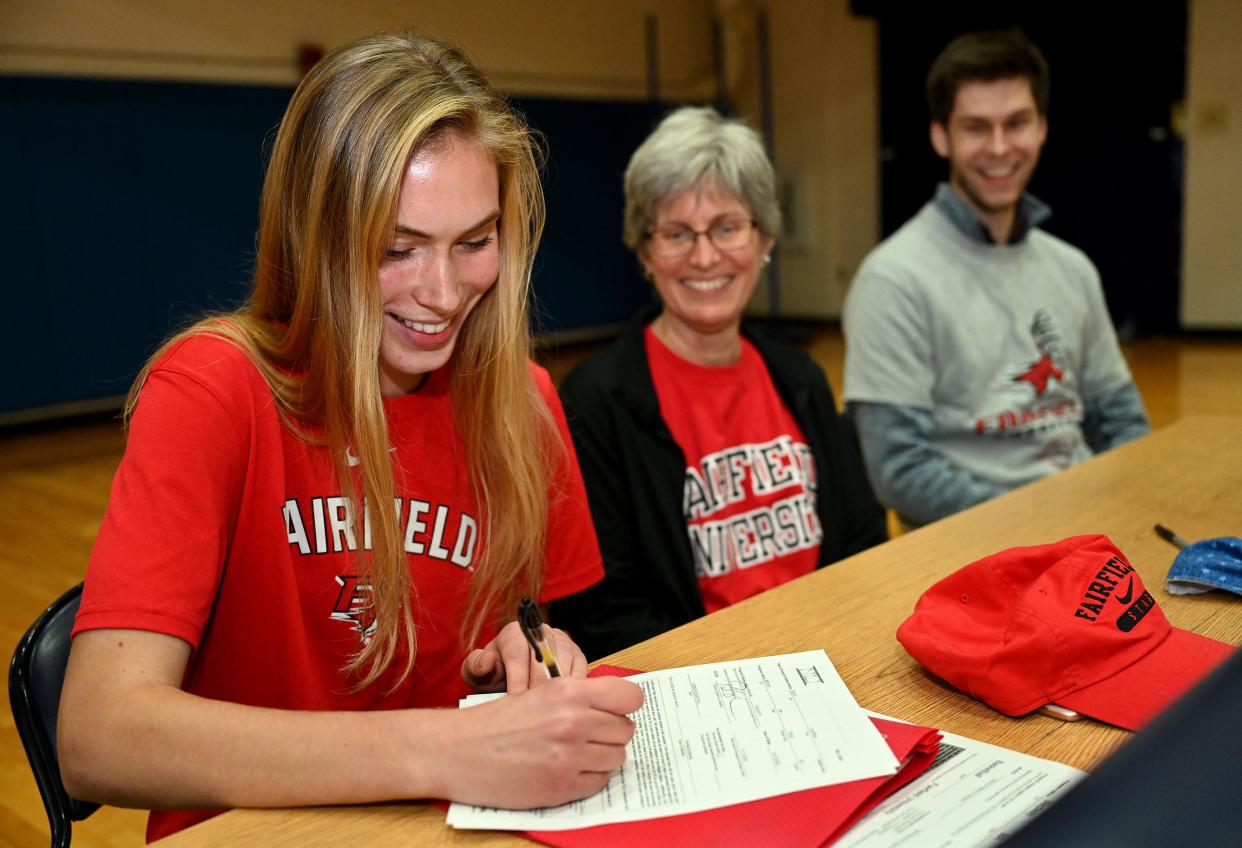 Medway High School senior Lauren Beach signs a National Letter of Intent to play basketball at Fairfield University, as her mother, Colleen, and brother Eric, 25, look on.