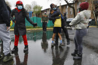 In this March 25, 2020, photo, volunteer Kevin Coleman, center, is hugged by a young man who he coached in little league football the previous year, as volunteers wait for people to come and get groceries they were delivering to an apartment complex in southeast Washington. At left is DC Ward 8 Councilman Trayon White. Neighborhood deliveries are part of a new Martha's Table initiative, along with community partners including Councilman White, to get needed food directly to the neighborhoods they serve. (AP Photo/Jacquelyn Martin)