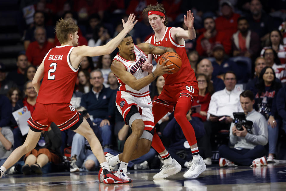 Arizona forward Keshad Johnson drives between Utah guard Cole Bajema and center Branden Carlson (35) during the first half of an NCAA college basketball game Saturday, Jan. 6, 2024, in Tucson, Ariz. (AP Photo/Chris Coduto)